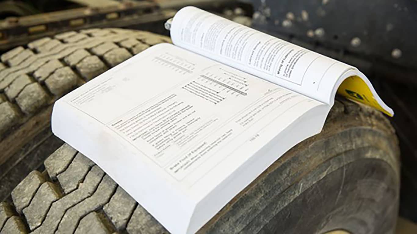 an open operator's manual laying on top of a tire