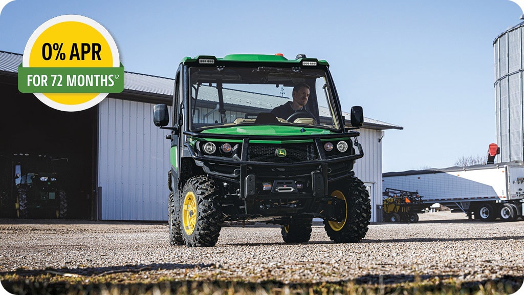 0% APR for 72 months advertisement showing a man in a John Deere XUV865R Series Gator utility vehicle turning its driving wheel.